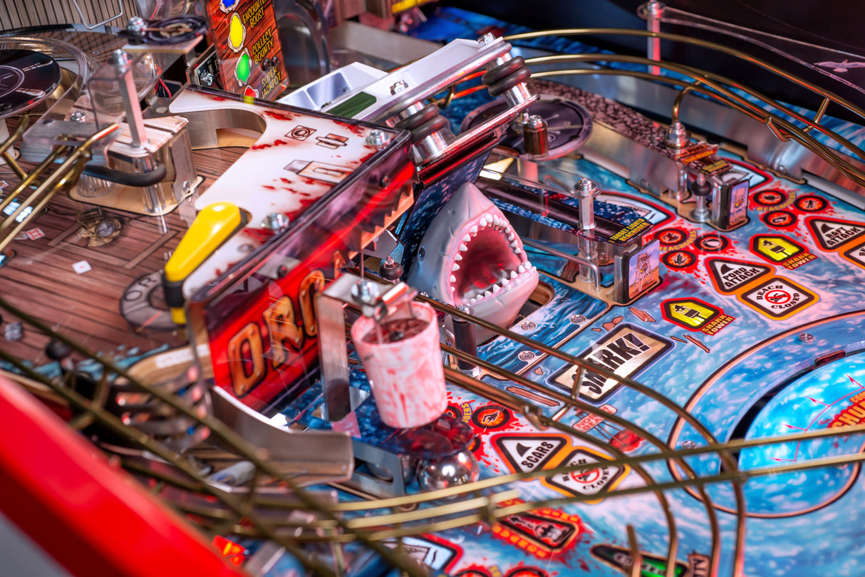 Close-up of Jaws 50th Anniversary pinball machine with a shark figure and colorful design.
